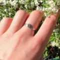 Primo piano del dettaglio dell'anello floreale inciso in argento indossato all'aperto con fiori. - n.5 / Argento