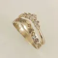 Close-up van de elegante stapelende ringenset met gegraveerde bloemenband en sprankelende ring. - Maat 5 / Goudkleur
