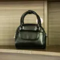 Dettaglio di piccola borsa a conchiglia nera con manico retro e accessori in argento. - Nero
