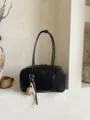 Λεπτομερής όψη της μινιμαλιστικής μαύρης τσάντας ώμου με κομψό διακοσμητικό μενταγιόν. - Μαύρο