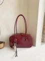 Λεπτομερής κοντινή άποψη της σκούρας κόκκινης μινιμαλιστικής γυναικείας τσάντας με διπλές λαβές. - Μπορντό