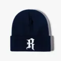Close-up of navy blue knit beanie featuring white gothic letter R embroidery detail. - Adjustable / Navy Blue