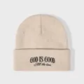 Gedetailleerde close-up van beige gebreide muts met zwarte geborduurde tekst, winter. - Verstelbaar / Beige