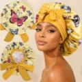 Detail shot of the butterfly print satin sleep bonnet with adjustable ribbon ties for hair care. - One Size / Yellow
