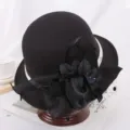 Chapeau melon en laine noire avec fleur élégante et voile, vue de détail style rétro. - M (56-58cm) / Fleur de Dentelle / Noir