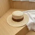 Detailed view of women's summer flat top straw hat with brown ribbon, elegant sun protection. - M (56-58cm) / Coffee