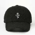 Close-up detail of black sherpa baseball cap with white rose and love embroidery motif. - Adjustable / Black