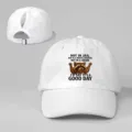 Detalle de gorra de béisbol blanca con coleta, diseño divertido de mapache y texto. - Ajustable / Blanco