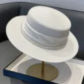 Détail élégant de chapeau de paille plat blanc avec bordure en perles et ruban de satin. - Réglable / Blanc