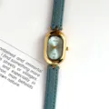 Detailed close-up view of women's vintage oval quartz watch featuring blue leather strap. - Gold Case Blue Dial Light Blue Strap