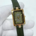 Detaillierte Nahaufnahme einer Vintage rechteckigen grünen Lederuhr mit römischen Ziffern. - Goldgehäuse Grünes Zifferblatt Grünes Armband