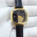 Gros plan detaille de montre quartz femme avec boitier carre dore et bracelet - Boîtier Or Cadran Noir Bracelet Noir