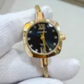 Primo piano dettagliato di orologio al quarzo dorato con quadrante nero e bracciale a cavo. - Quadrante Nero Oro