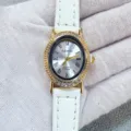 Gros plan sur une montre quartz femme avec bracelet en cuir blanc et lunette ovale strassée. - Boîtier Doré Cadran Blanc Bracelet Blanc