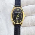 Gros plan détaillé d'une montre quartz pour femme avec boîtier doré ovale et bracelet en cuir noir. - Boîtier Or Cadran Noir Bracelet Noir