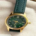Elegante Damenuhr mit grünem Zifferblatt, goldenem Gehäuse und dunklem Lederarmband. - Goldgehäuse Grünes Zifferblatt Grünes Armband