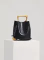 Stylish black leather bucket bag with unique gold handle and sphere accent for women fashion. - Black