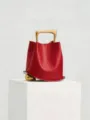 Red leather bucket bag with unique gold handle and sphere accent, stylish niche fashion accessory. - Red