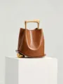 Chic autumn winter brown leather bucket bag featuring unique gold metal handle detail. - Brown
