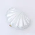 Close-up of pearlescent acrylic shell clutch detail, elegant gold metal clasp texture. - White
