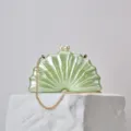 Pearl clasp and acrylic shell texture detail view of the elegant party clutch bag accessory. - Green