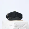 Nahaufnahme Detail der eleganten schwarzen Acryl Abendtasche mit edler goldener Kette. - Schwarz