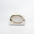 Detail view of white evening clutch bag featuring a sleek large gold metallic ring handle design. - White