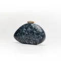 Detailed view of grey marble acrylic evening clutch bag with textured gold clasp hardware. - Black