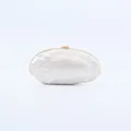 Detailed close-up of the glossy acrylic shell evening clutch with gold metal clasp. - White