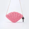 Pink shell-shaped straw woven crossbody bag with delicate chain strap and chic dark charm. - Pink