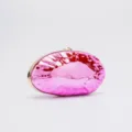 Close-up of glossy pink acrylic evening clutch bag with gold-tone metal frame and clasp detail. - Pink