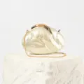 Close-up detail of pearl acrylic evening clutch bag with elegant gold leaf lock and chain strap. - White