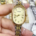 Gros plan sur la montre à quartz ovale SUNLIFEX avec chiffres romains et bracelet acier. - Cadran Or Bicolore