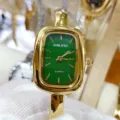 Close-up detail of green dial square quartz watch with gold metal case and bangle strap. - Gold Green Dial