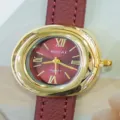 Women's elegant quartz watch featuring an oval gold-tone case and red leather strap. - Red