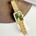 Vista dettagliata dell'orologio vintage con quadrante rettangolare e cinturino dorato. - Cassa Oro Quadrante Verde