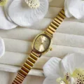 Gros plan détaillé de la montre élégante pour femme dorée ovale avec bracelet jonc en bambou. - Cadran Or Or