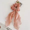 Detailansicht des rosa Chiffon Haargummis mit eleganten langen fließenden Bändern. - Rosa