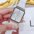 Detailansicht der quadratischen WOVE Quarzuhr mit weißem Silikonarmband und goldenem Gehäuse. - Weiß