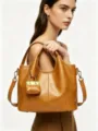 Close-up detail of the brown leather bucket bag showing fine texture and cute mini charm. - 24CM*11CM*20CM / Maple Leaf Yellow