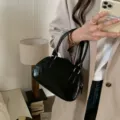 Black patent leather bowling bag, stylish women underarm handbag with top handle and metal hardware. - Black