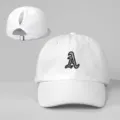 Detailaufnahme der weißen Zopfbaseballkappe mit gesticktem Buchstaben A und Metallverschluss. - Verstellbar / Weiß