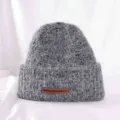 Detailed view of grey fuzzy knitted beanie hat with brown leather tag, cozy winter headwear. - M (56-58cm) / Dark Gray