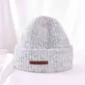 Detailed close-up view of thick warm grey knit beanie hat featuring chic leather patch label. - M (56-58cm) / Light Gray