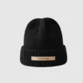 Close-up detail view of the black knitted winter beanie featuring a stylish leather label. - M (56-58cm) / Black