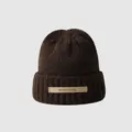 Close-up detail of the brown knitted beanie with a front leather label and soft texture. - M (56-58cm) / Coffee