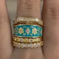 Gedetailleerde close-up van vintage paleisstijl gestapelde ringen set met strik en blauw bloememaille. - Maat 6 / Goud