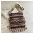 Vue détaillée du sac bandoulière ethnique rétro tissé avec des pompons colorés et des motifs. - Rouge