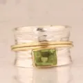 Primer plano detallado de un anillo ancho bicolor con una piedra verde y textura martillada. - Talla 6 / Dos colores