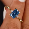 Vista detallada de un anillo de lujo con circonita azul de corte rectangular y piedras laterales. - Talla 5 / Azul
